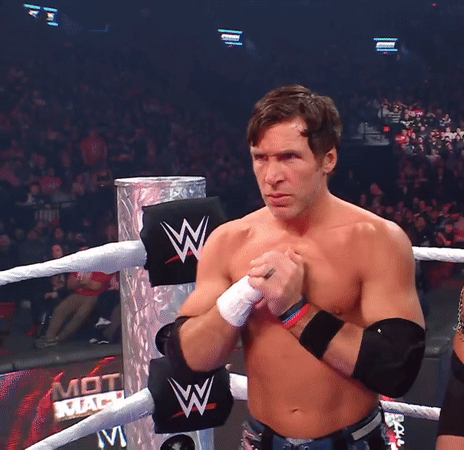 A Shirtless Wrestler Stands In A Ring With A Sign That Says Mot Mach On It GIF