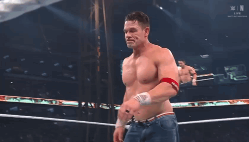 A Shirtless Wrestler Stands In A Wrestling Ring With A Banner That Says Smackdown On It GIF