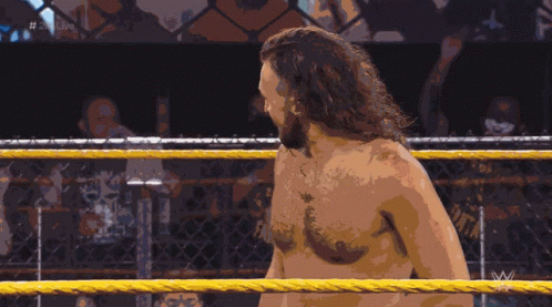 A Shirtless Wrestler Stands In A Wrestling Ring With The Letters W On The Bottom Right GIF