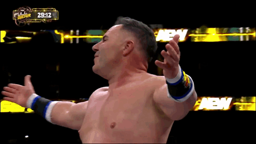 A Shirtless Wrestler Stands In Front Of A Full Gear Banner GIF