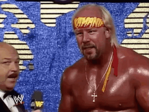 A Shirtless Wrestler Wearing A Headband That Says Hulk Hogan Is Talking To A Microphone . GIF
