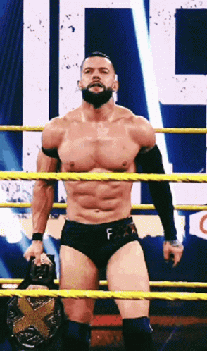A Shirtless Wrestler With A Beard Is Standing In A Ring Holding A Belt . GIF