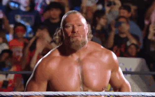 A Shirtless Wrestler With A Beard Is Standing In A Wrestling Ring . GIF