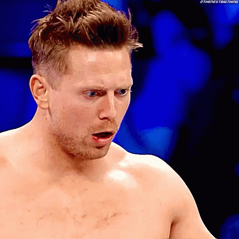 A Shirtless Wrestler With A Surprised Look On His Face And A Blue Background GIF