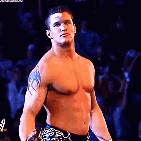 A Shirtless Wrestling Wrestler With A Bandage On His Forehead Is Standing In Front Of A Crowd . GIF