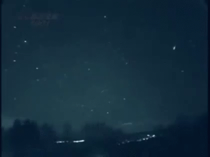 A Shooting Star Is Flying Through A Dark Night Sky . GIF