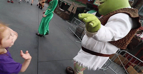 A Shrek Mascot Standing Next To A Little Girl In A Purple Shirt GIF