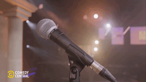 A Shure Microphone On A Stand With Comedy Central Written On The Bottom GIF