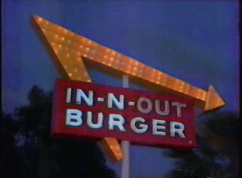 A Sign For An In-N-Out Burger Restaurant Is Lit Up At Night GIF