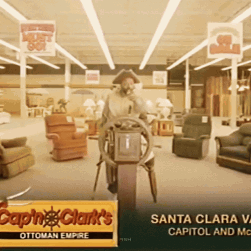 A Sign For Capn Clark 'S Ottoman Empire Shows A Man At The Steering Wheel GIF