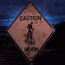 a sign that says caution full moon with a person looking through binoculars