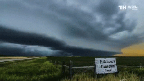 A Sign That Says Hitchcock Museum Free In Front Of A Storm GIF