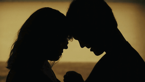A Silhouette Of A Man And A Woman Holding Hands GIF