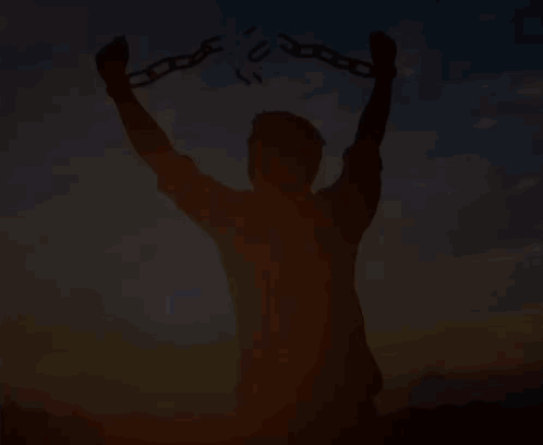 A Silhouette Of A Man Holding Chains In His Hands At Sunset . GIF