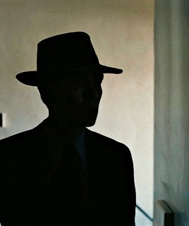 A Silhouette Of A Man In A Hat And Suit GIF
