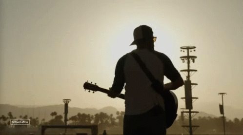 A Silhouette Of A Man Playing A Guitar With A Sign That Says ' Silhouette ' On It GIF