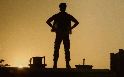 A Silhouette Of A Man Standing With His Hands On His Hips At Sunset GIF
