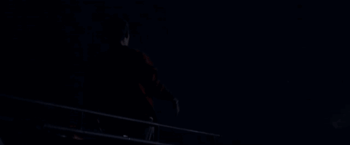 A Silhouette Of A Man With His Arms Outstretched Against A Dark Blue Sky GIF