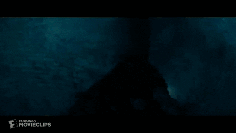 a silhouette of a person in a dark room with a light coming out of the ceiling .