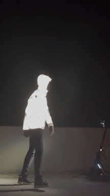 A Silhouette Of A Person In A Reflective Jacket Is Visible In The Dark GIF