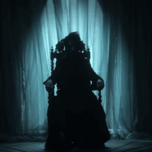 A Silhouette Of A Person Sitting In A Dark Room GIF