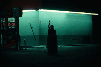 A Silhouette Of A Person Standing In Front Of A Gas Station With A Sign That Says Pepsi GIF