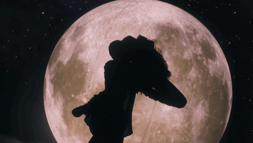 A Silhouette Of A Person Standing In Front Of The Full Moon GIF