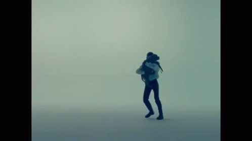 A Silhouette Of A Person With A Backpack Standing In The Fog GIF