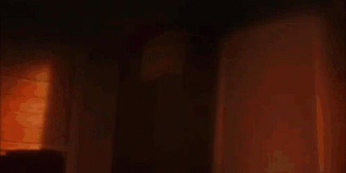 A Silhouette Of A Woman With Glowing Eyes Is Standing In An Open Doorway GIF