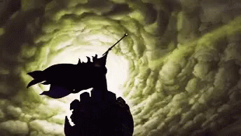 A Silhouette Of Batman Flying Through A Cloudy Sky GIF