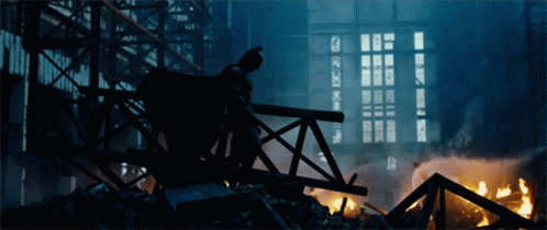 A Silhouette Of Batman Standing On A Bridge In Front Of A Building GIF