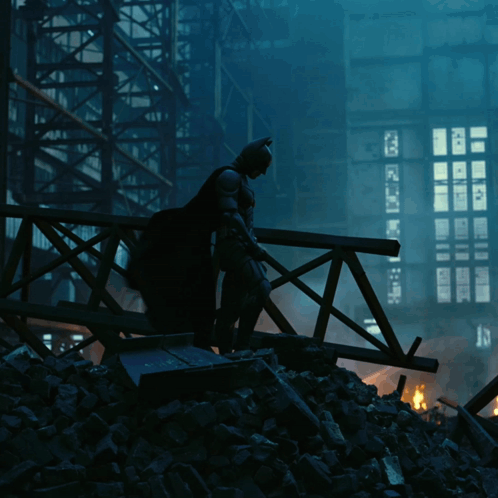 A Silhouette Of Batman Standing On A Bridge With A Building In The Background GIF