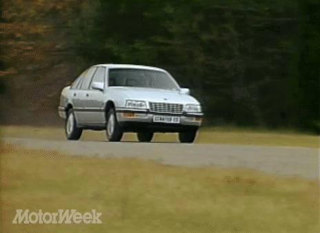 A Silver Car Is Driving Down A Road With Motorweek Written On The Bottom Right GIF