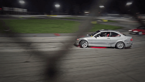 A Silver Car Is Driving On A Dirt Road At Night GIF
