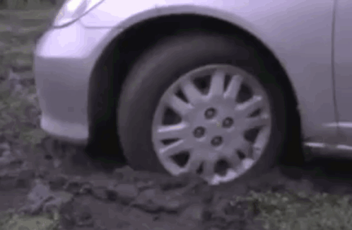 A Silver Car Is Stuck In A Muddy Area . GIF