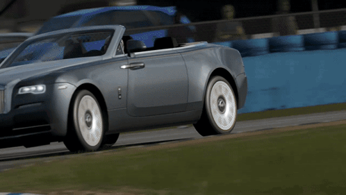 A Silver Convertible Rolls Royce Driving On A Track GIF
