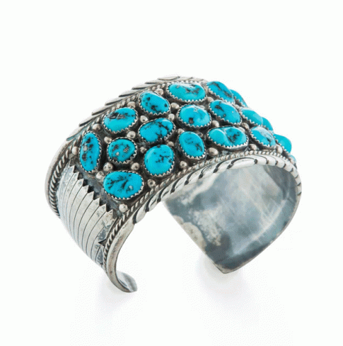 A Silver Cuff Bracelet With Turquoise Stones On A White Background GIF