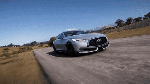 A Silver Infiniti Is Driving Down A Road With Mountains In The Background GIF