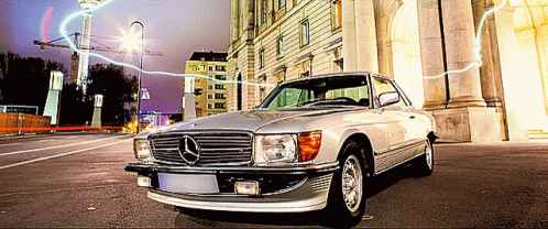 A Silver Mercedes Is Parked On The Street In Front Of A Building GIF