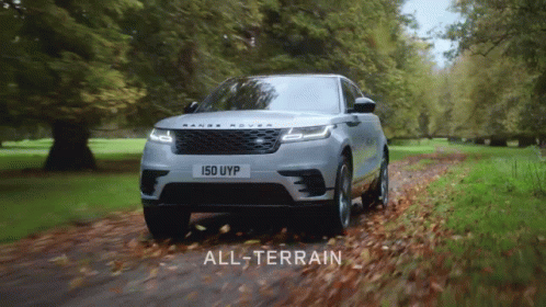 A Silver Range Rover Is Driving Down A Road With Leaves On The Ground GIF