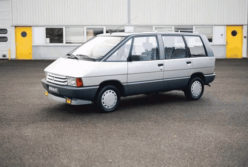 A Silver Renault Minivan Is Parked In Front Of A Building GIF