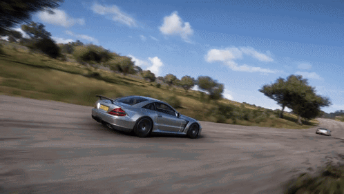 A Silver Sports Car Is Driving Down A Dirt Road With A Yellow License Plate GIF