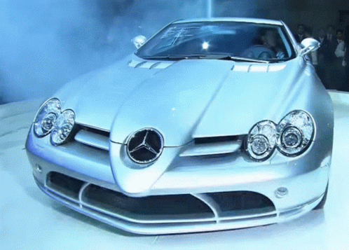 A Silver Sports Car With A Mercedes Logo On It GIF