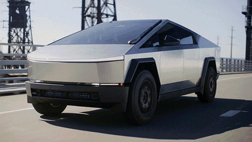 A Silver Tesla Cybertruck Is Driving Down A Bridge GIF