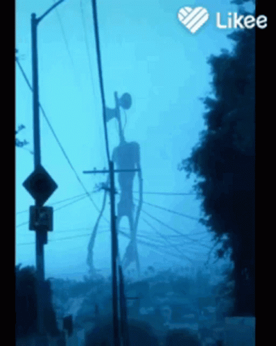 A Siren Head Is Silhouetted Against A Blue Sky Behind Telephone Poles GIF