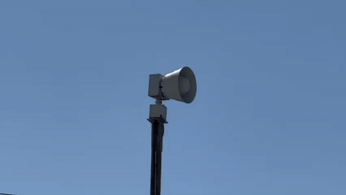 A Siren Is Sitting On Top Of A Pole In The Sky . GIF