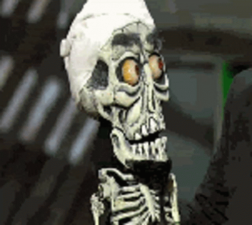 A Skeleton Wearing A Bandage On Its Head Is Holding A Microphone . GIF