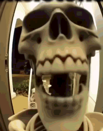 A Skeleton With Its Mouth Open Is Standing In A Doorway GIF