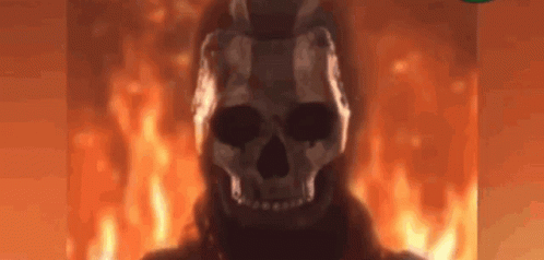A Skull Is Standing In Front Of A Fire In A Dark Room . GIF