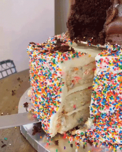 A Slice Of Cake With Sprinkles On It Is Being Cut GIF